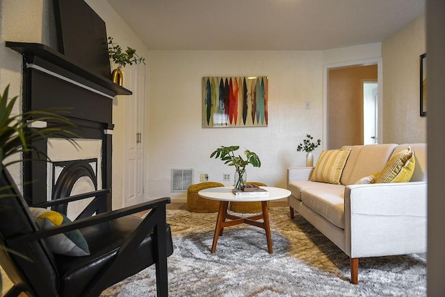 living area with visible vents, a fireplace, and a textured wall