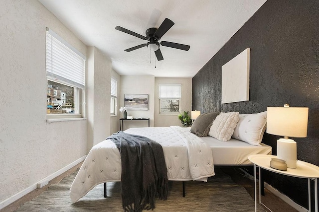 bedroom featuring baseboards, a ceiling fan, and a textured wall