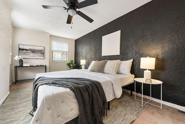 carpeted bedroom with an accent wall, visible vents, a ceiling fan, and baseboards