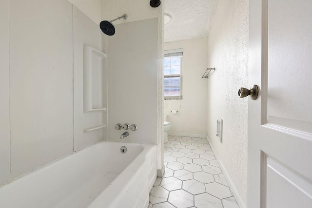 full bath with baseboards, washtub / shower combination, toilet, tile patterned floors, and a textured ceiling