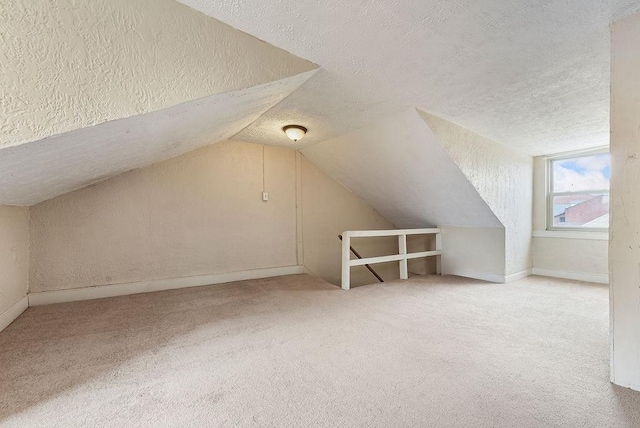 bonus room with carpet flooring, a textured ceiling, a textured wall, and vaulted ceiling