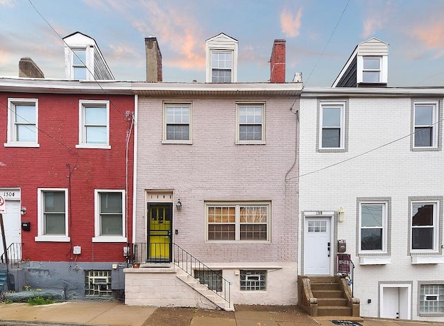 view of front of home with brick siding, entry steps, and a chimney