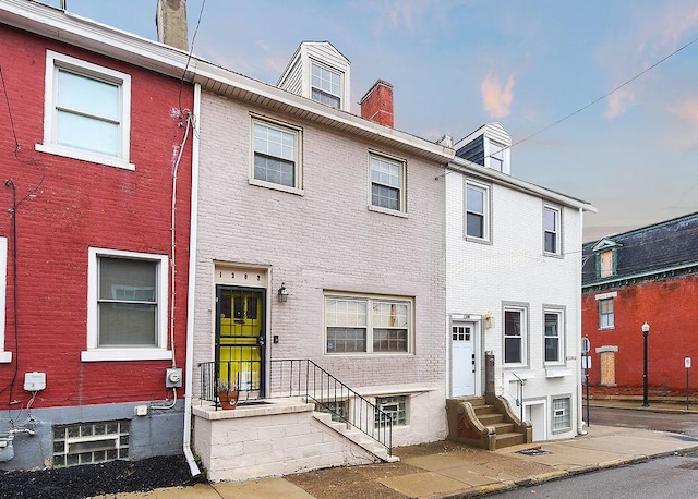 townhome / multi-family property featuring brick siding, a chimney, and entry steps