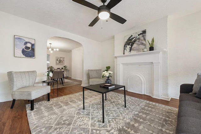 living room featuring arched walkways, baseboards, and wood finished floors