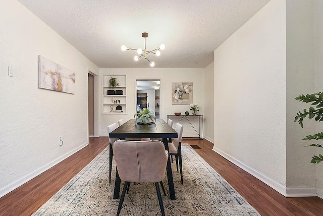 dining space featuring a notable chandelier, built in shelves, dark wood-style floors, and a textured ceiling