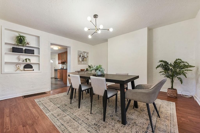 dining space with wood finished floors, visible vents, a chandelier, and a textured ceiling