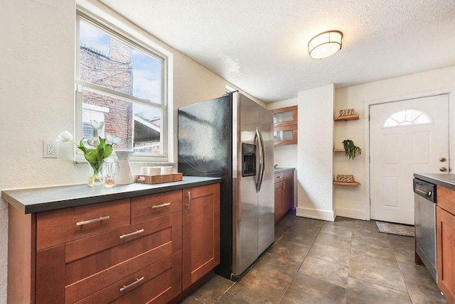 kitchen with open shelves, stainless steel appliances, a textured ceiling, dark countertops, and a textured wall