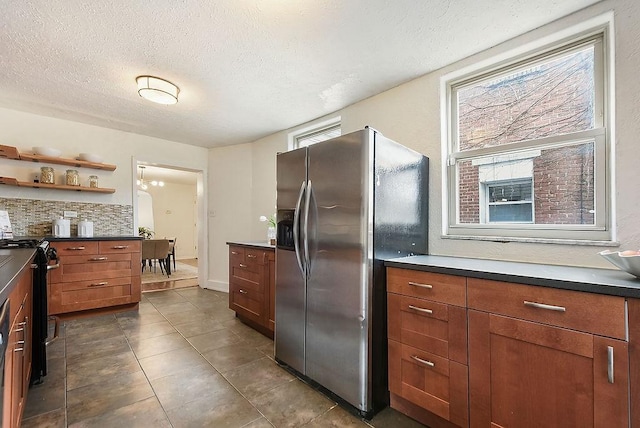 kitchen with range, plenty of natural light, dark countertops, and stainless steel refrigerator with ice dispenser