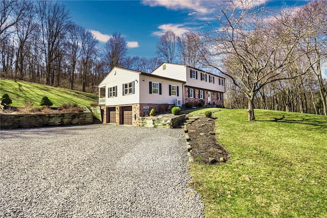 colonial-style house featuring a front lawn, an attached garage, stone siding, and driveway