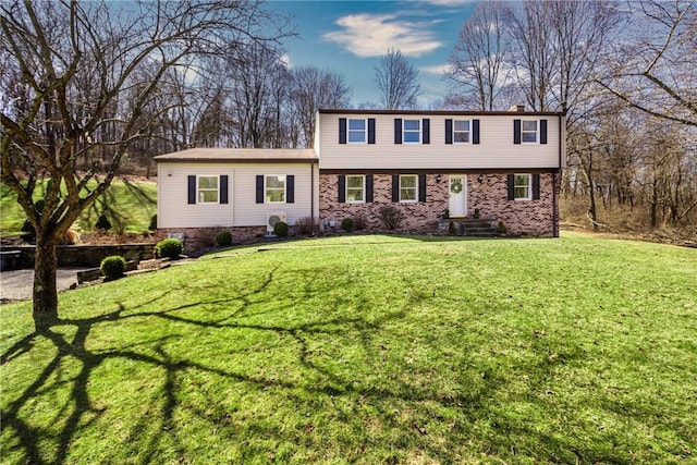 colonial-style house featuring a front yard and brick siding