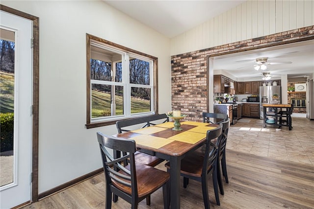 dining space with a ceiling fan, light wood-style floors, and baseboards