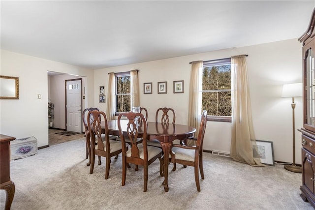 dining area featuring light carpet, visible vents, and baseboards