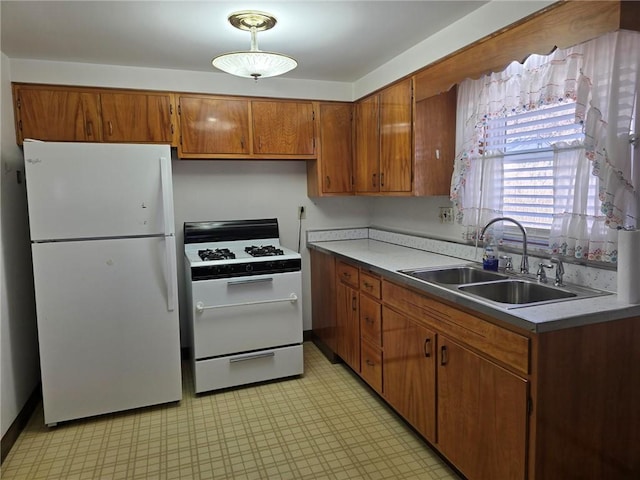 kitchen featuring a sink, white appliances, light floors, and brown cabinets