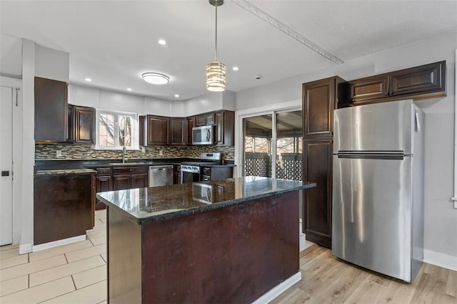 kitchen with light wood-style flooring, a sink, backsplash, appliances with stainless steel finishes, and dark brown cabinets