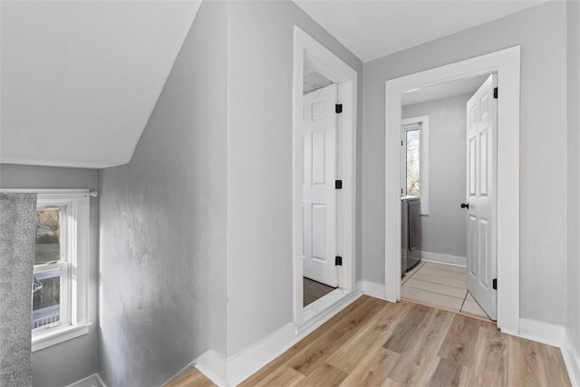 hallway featuring baseboards and light wood-style floors