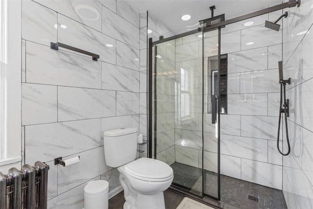 bathroom featuring tile walls, toilet, a shower stall, and radiator heating unit