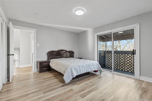 bedroom featuring access to outside, baseboards, and light wood-type flooring