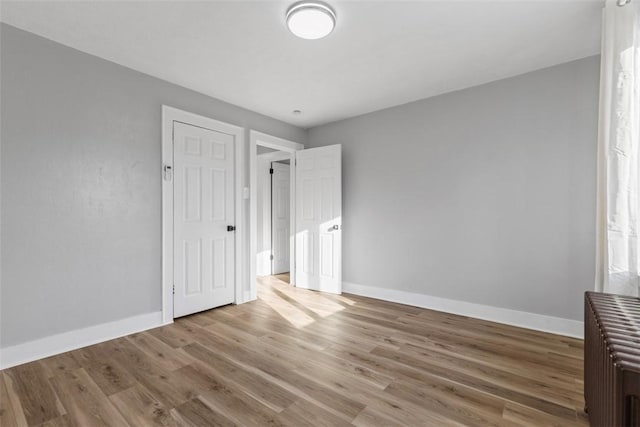 unfurnished bedroom featuring wood finished floors and baseboards