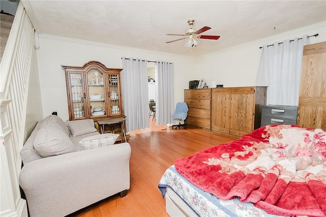 bedroom with light wood-type flooring, a ceiling fan, and crown molding