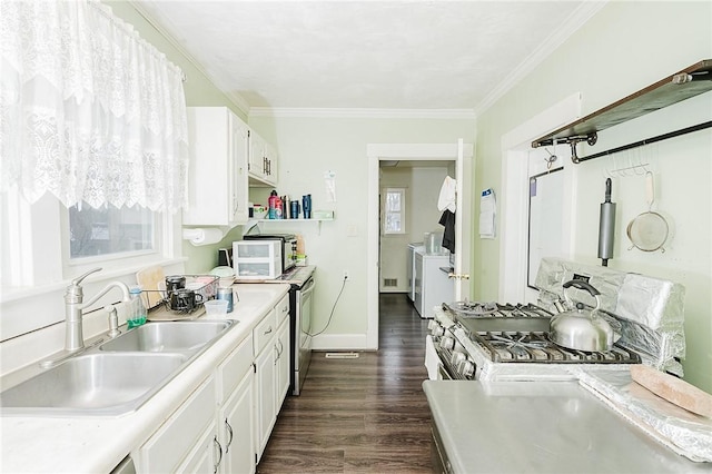 kitchen with washing machine and dryer, light countertops, white cabinets, gas stove, and a sink