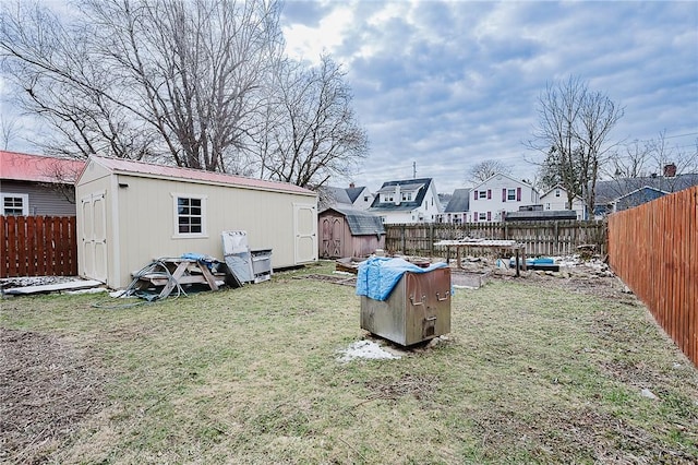 view of yard with a storage unit, an outbuilding, and a fenced backyard