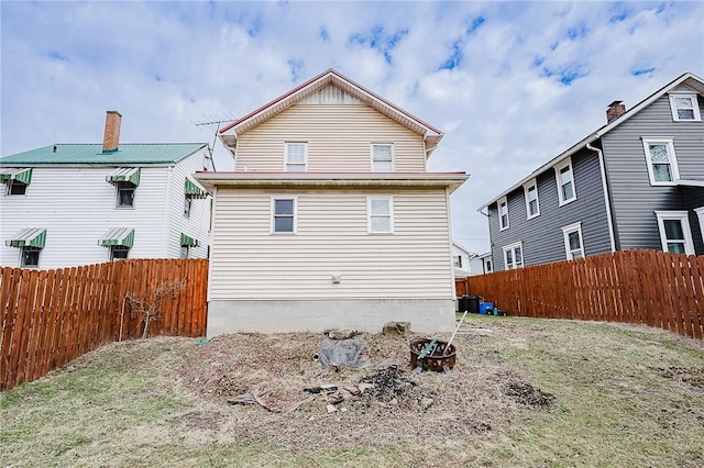 back of property with fence and an outdoor fire pit