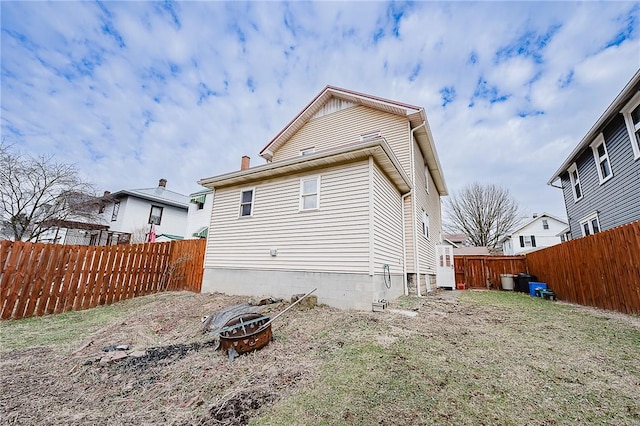 rear view of house featuring a fire pit and a fenced backyard