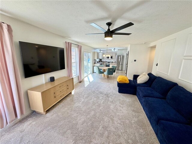 living room with light carpet, a textured ceiling, and a ceiling fan