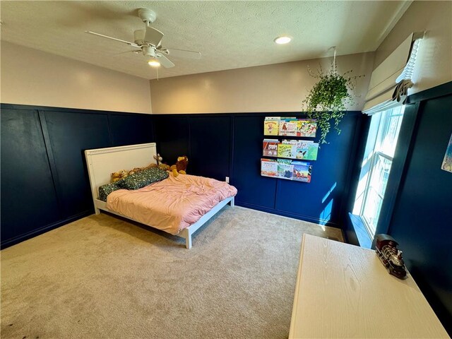 bedroom with a textured ceiling, carpet, and a ceiling fan