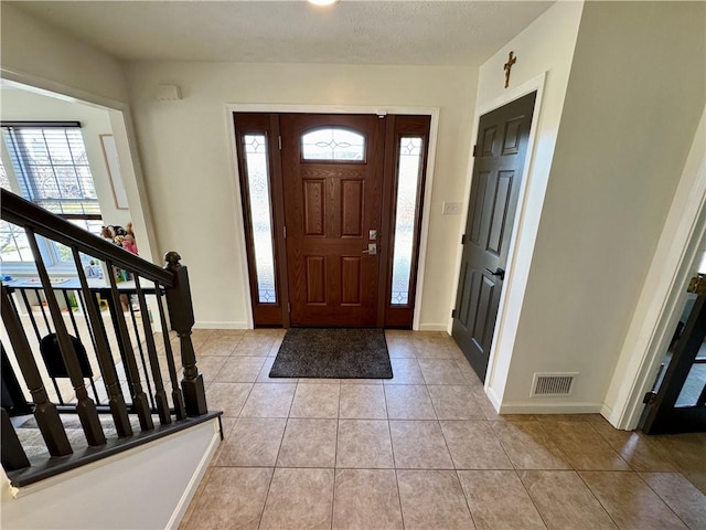 entryway featuring light tile patterned floors, baseboards, visible vents, stairs, and a textured ceiling