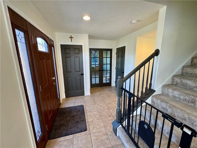 entrance foyer featuring light tile patterned floors, stairway, french doors, and baseboards