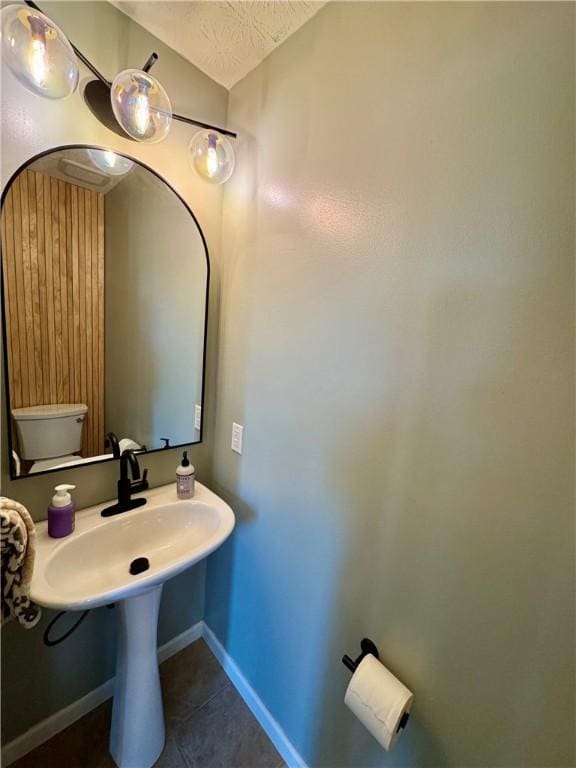 bathroom with tile patterned flooring, a textured ceiling, and baseboards