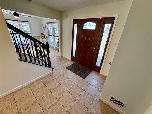 entrance foyer with light tile patterned floors, visible vents, stairs, and baseboards