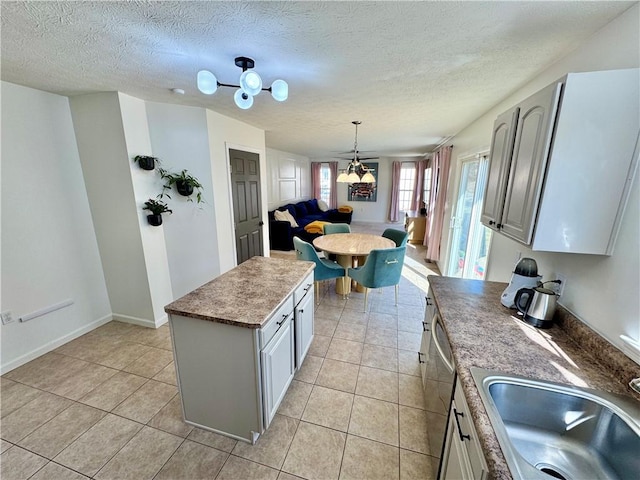 kitchen with light tile patterned floors, hanging light fixtures, a textured ceiling, and a sink