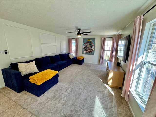 carpeted living area with a decorative wall, a ceiling fan, and a textured ceiling