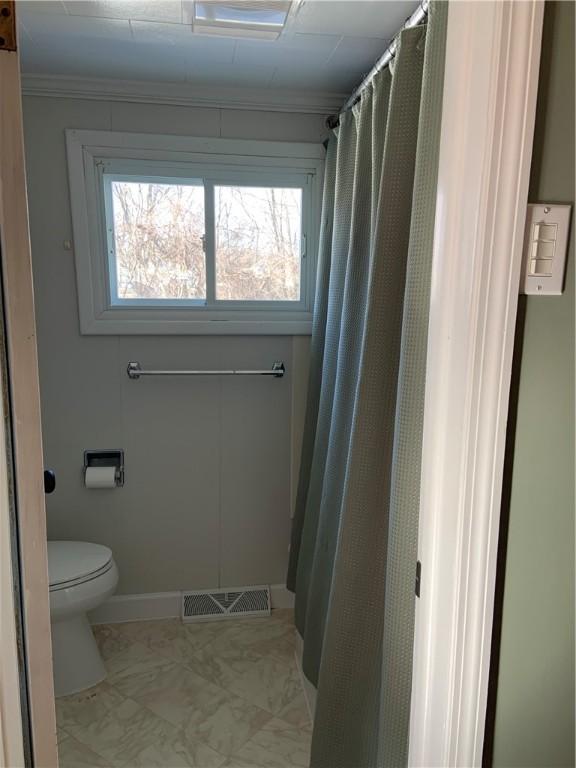 bathroom featuring toilet, baseboards, visible vents, and ornamental molding