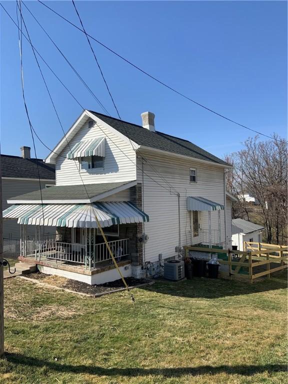 rear view of house featuring central air condition unit, a lawn, and a chimney