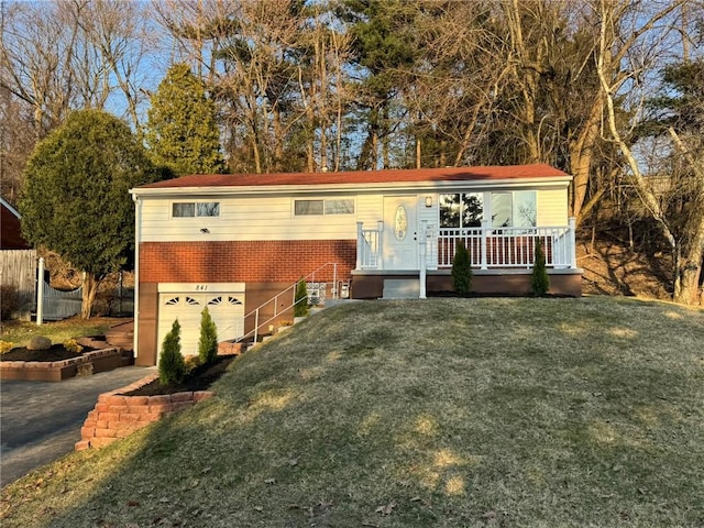 view of front of house with brick siding, a front yard, covered porch, and an attached garage