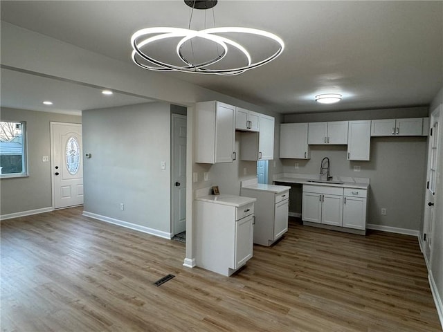 kitchen featuring a sink, baseboards, wood finished floors, and recessed lighting