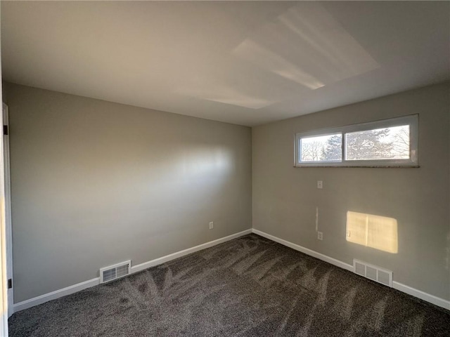 spare room featuring dark colored carpet, visible vents, and baseboards