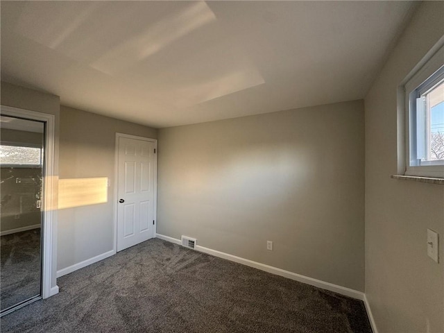 unfurnished bedroom featuring visible vents, baseboards, and dark carpet