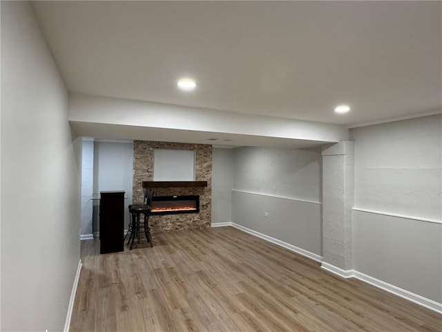 finished basement with wood finished floors, recessed lighting, a fireplace, and baseboards