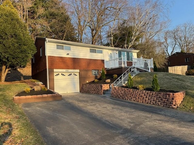 view of front of property with a garage, brick siding, driveway, and stairway