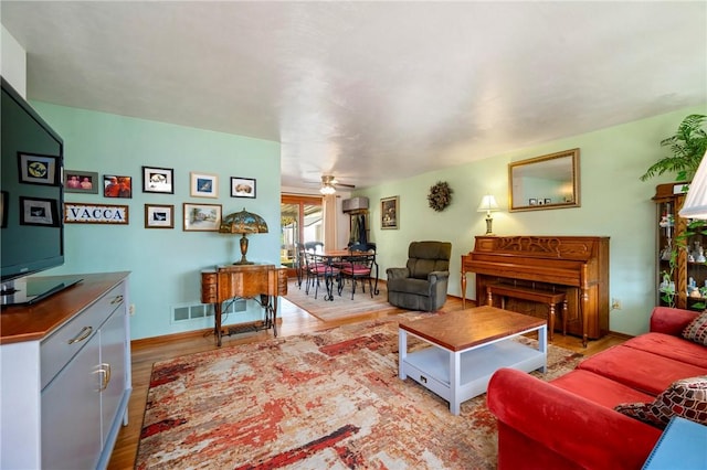 living room featuring visible vents, a ceiling fan, and wood finished floors