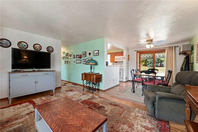 living room featuring baseboards, light wood-style flooring, and a ceiling fan