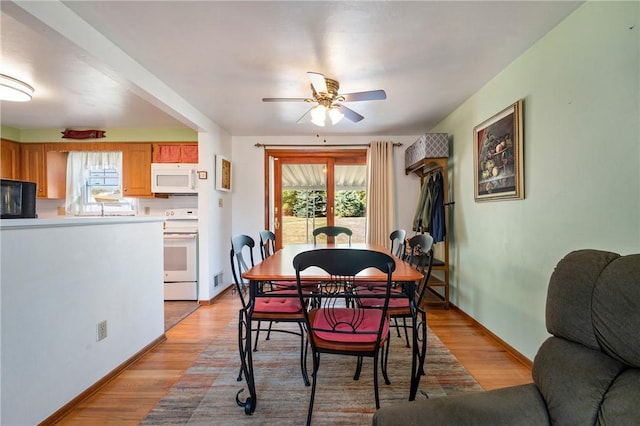 dining space with baseboards, a ceiling fan, and light wood finished floors