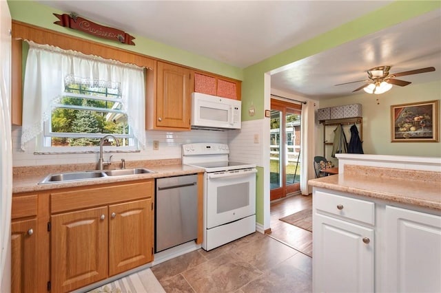 kitchen with a sink, white appliances, backsplash, and light countertops