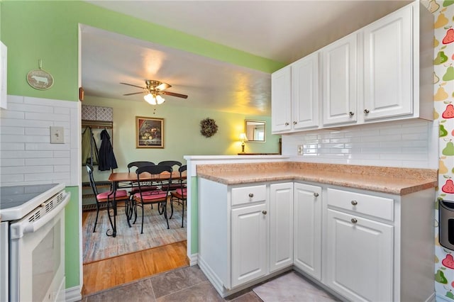 kitchen with light countertops, electric range, a peninsula, and white cabinets