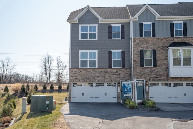 multi unit property featuring stone siding, board and batten siding, concrete driveway, and a garage