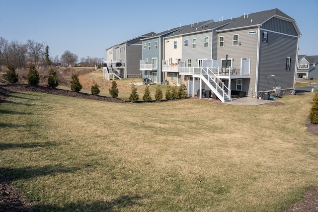 rear view of house featuring stairs, a lawn, a residential view, and a wooden deck